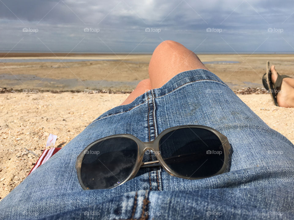 Relaxing on the beach woman in denim jean skirt sunglasses