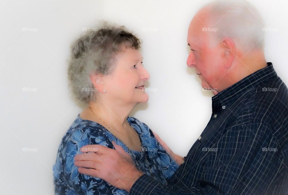 A couple in their late 70's looking into one another one's eyes with adoration and love. 