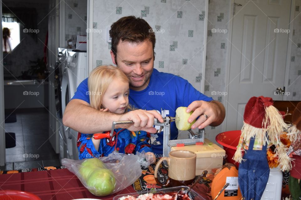 A dad teaching his daughter how to bake an apple pie