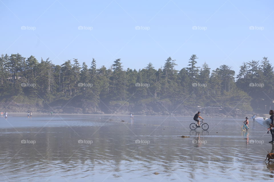 Boy riding bicycle on wide beach during low tide