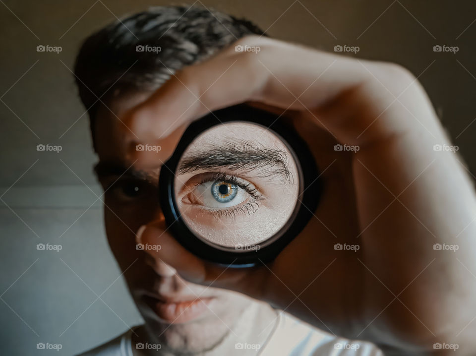 Close-up portrait of young boy looking through magnifying glass.