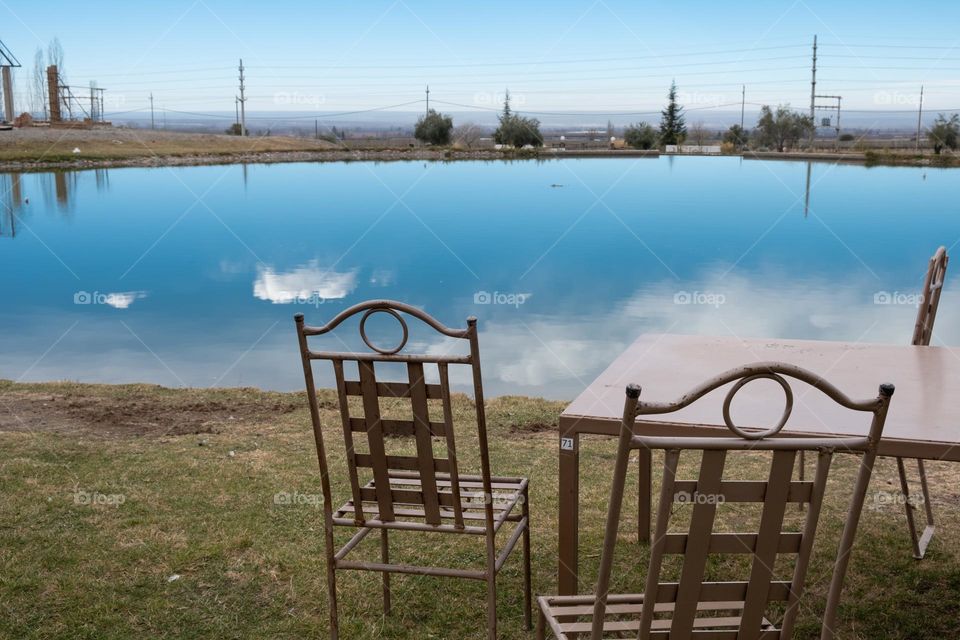 Cafe with metal furniture on the shore of a small blue lake