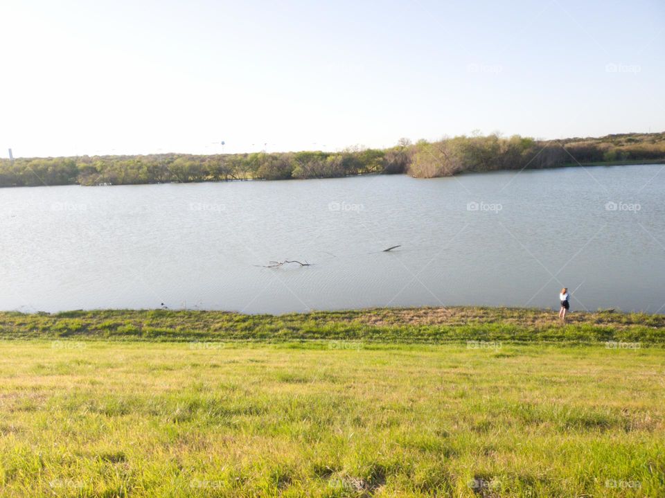 Young woman fishing at city park pond.