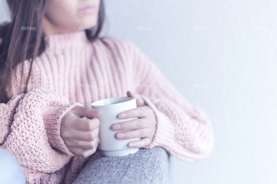 A woman wearing a cozy sweater and holding a cup