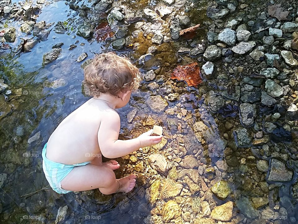 toddler playing in the creek
