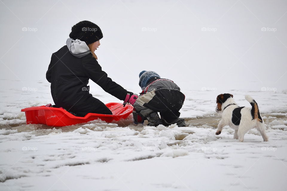 Two children playing on snowy landscape with dog