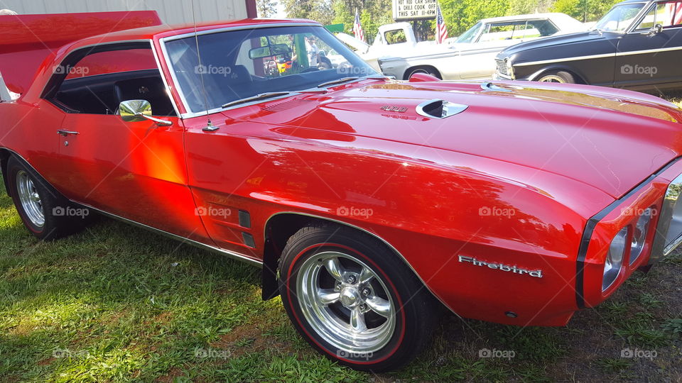 A classic red Pontiac Firebird 400 being displayed at a car show.