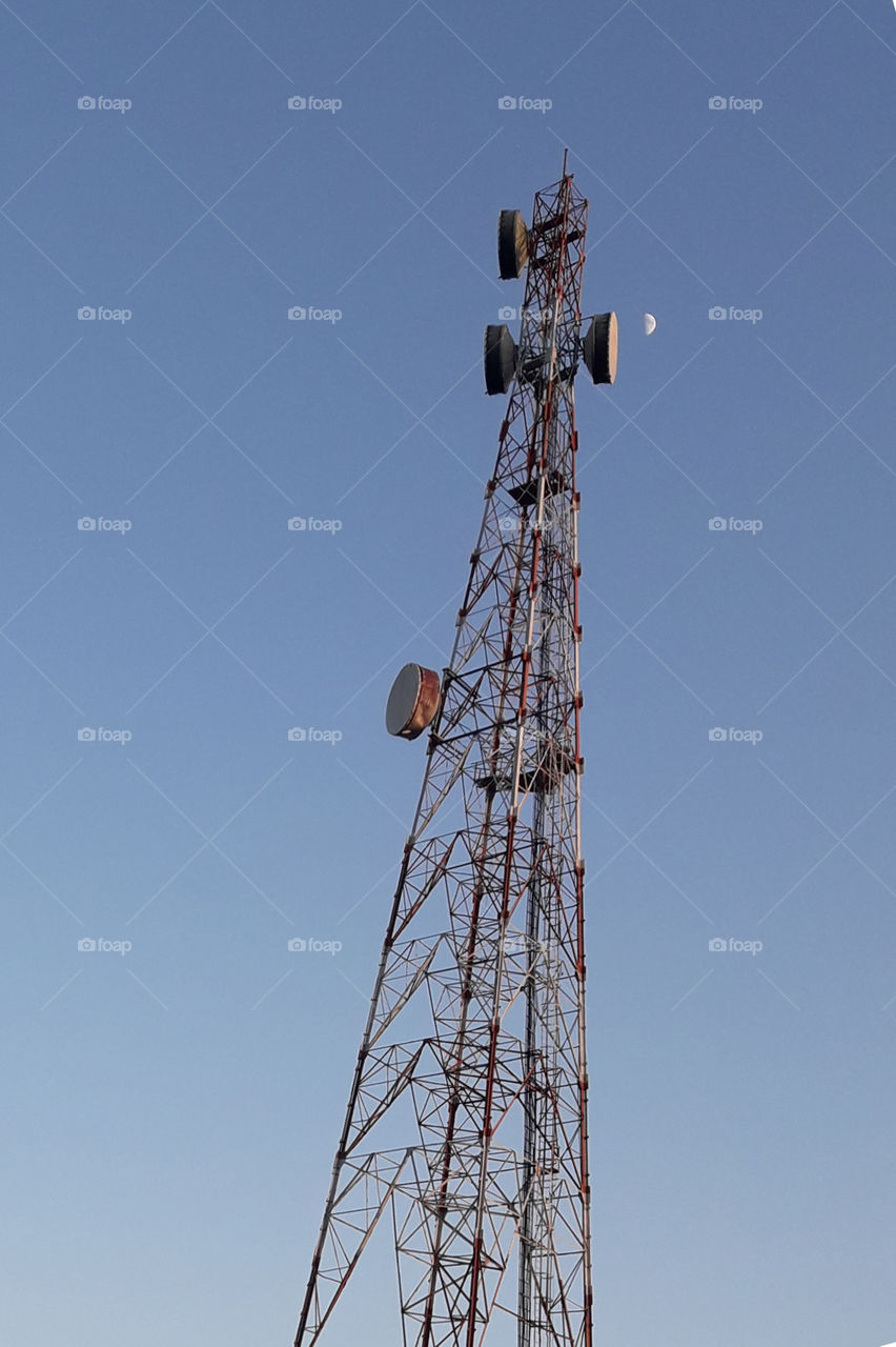 Mobile phone Tower with blue clean sky and moon.