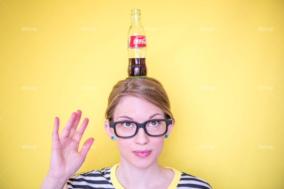 Bright, colorful portrait of a young woman balancing a bottle of Coca-cola on her head