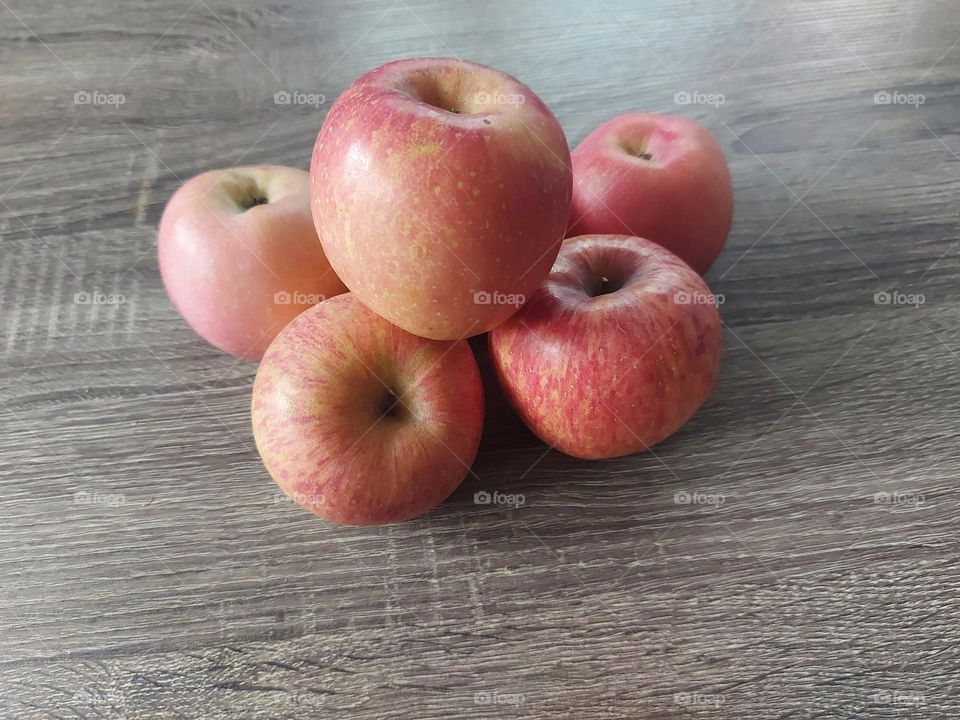 A few red apples placed on a wooden table