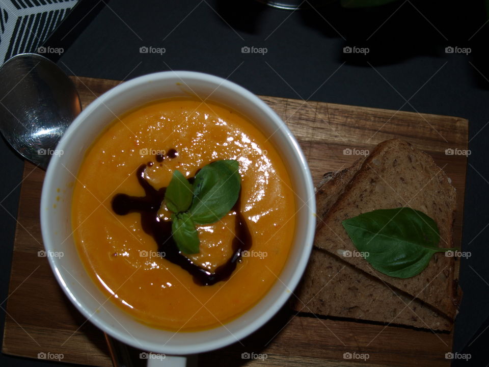 delicious and hot pumpkin soup decorated with basil and fresh bread on the side