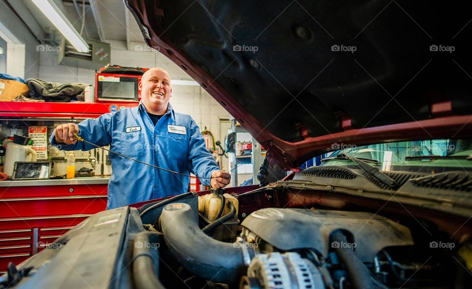 Mechanic laughing while looking at engine