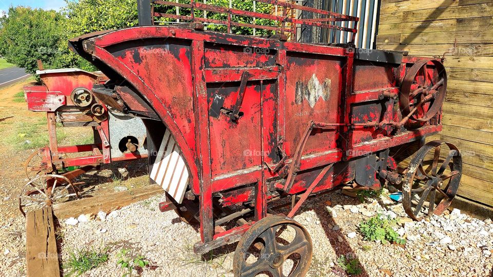 Trilhadeira, ferramenta antiga utilizada na colheita de grãos, agora deteriorando no espaço urbano.