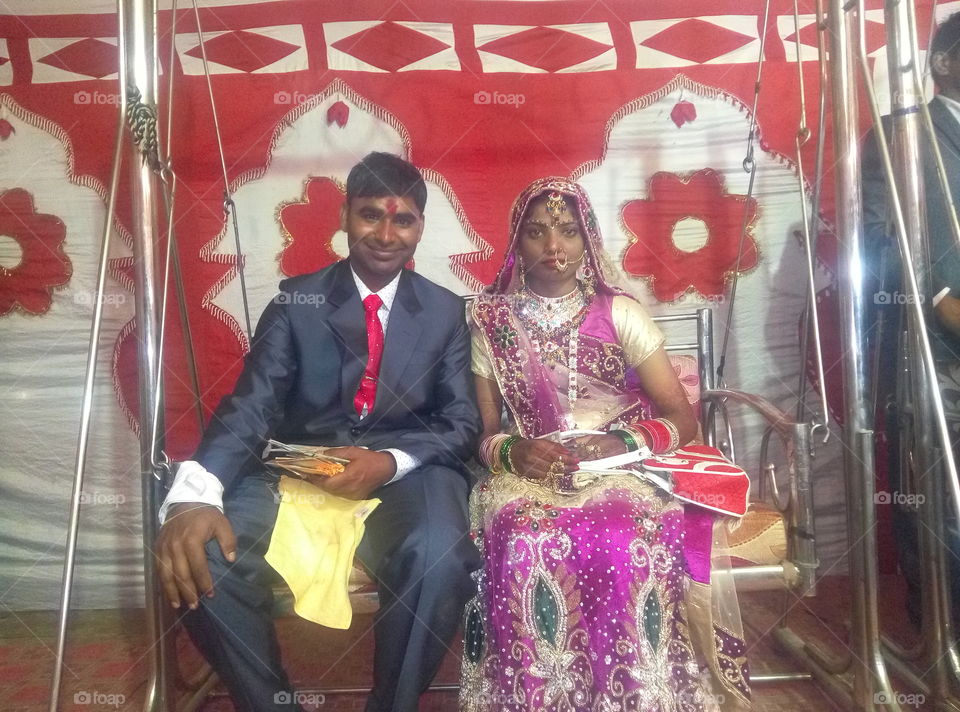 Indian bride and groom sitting on swing