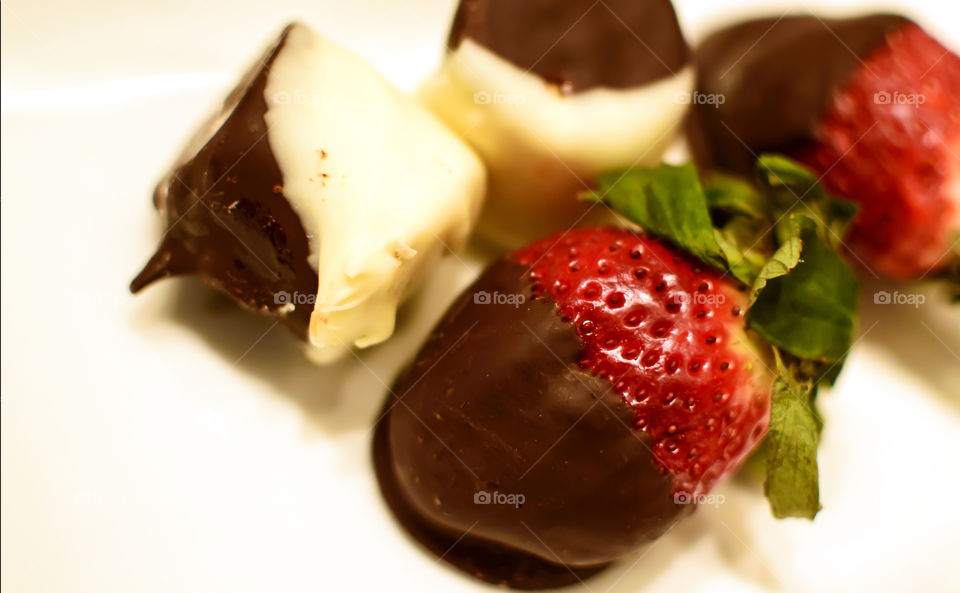 Chocolate covered fruit strawberry and banana pieces dipped in black and white rich dark chocolate 