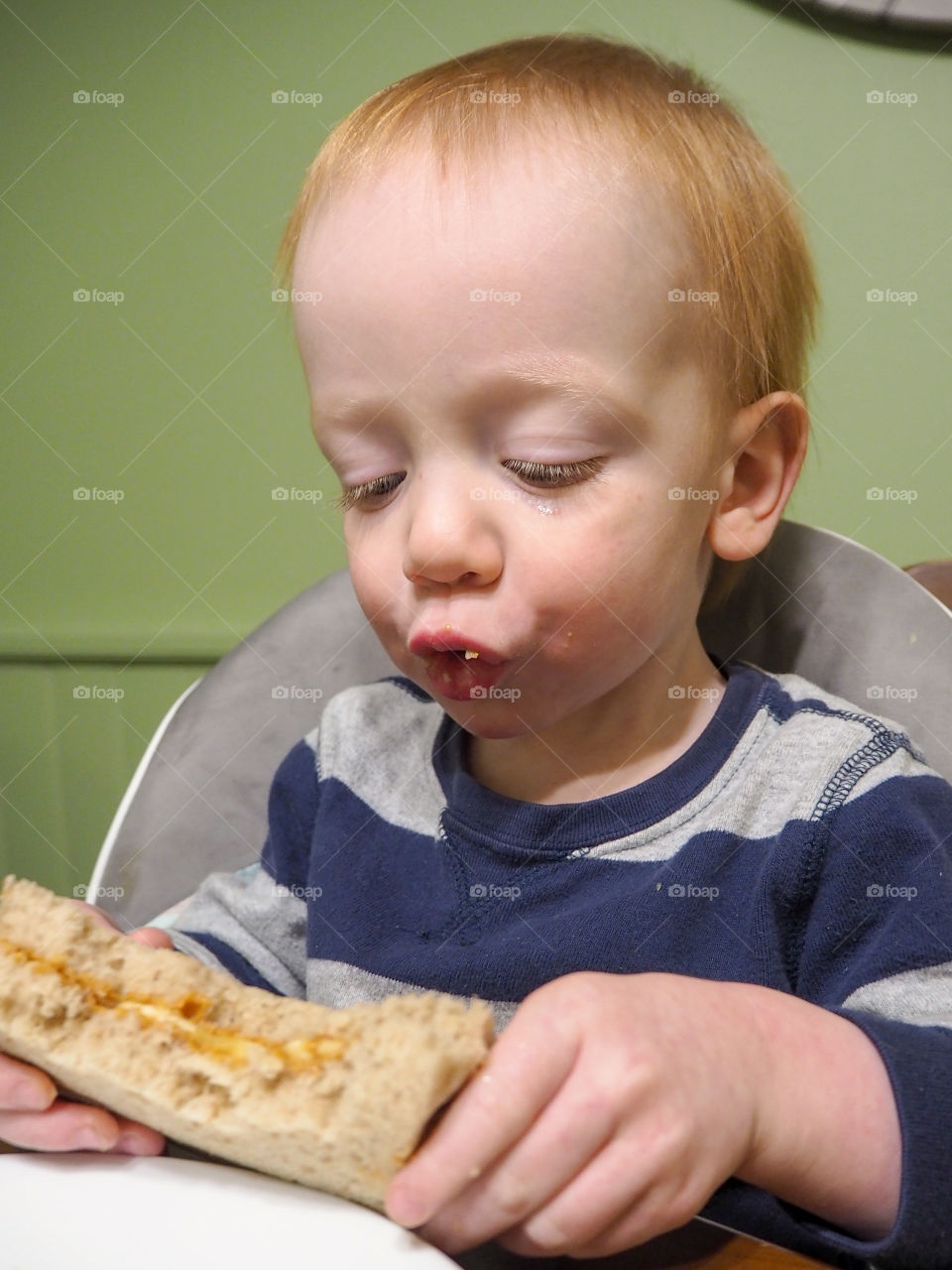 Toddler boy enjoying his peanut butter and banana sandwich