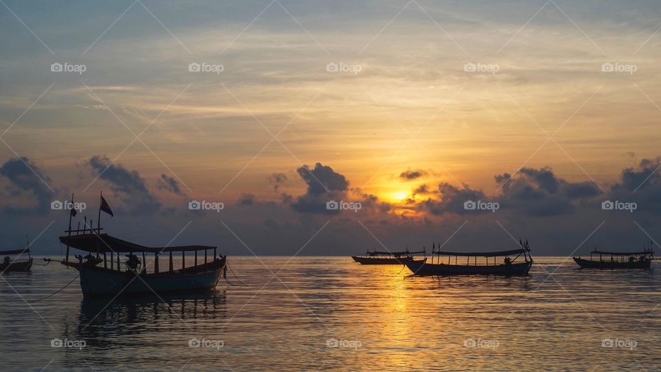 Longboats on the water at sunrise from the island of Koh Rong in Cambodia 