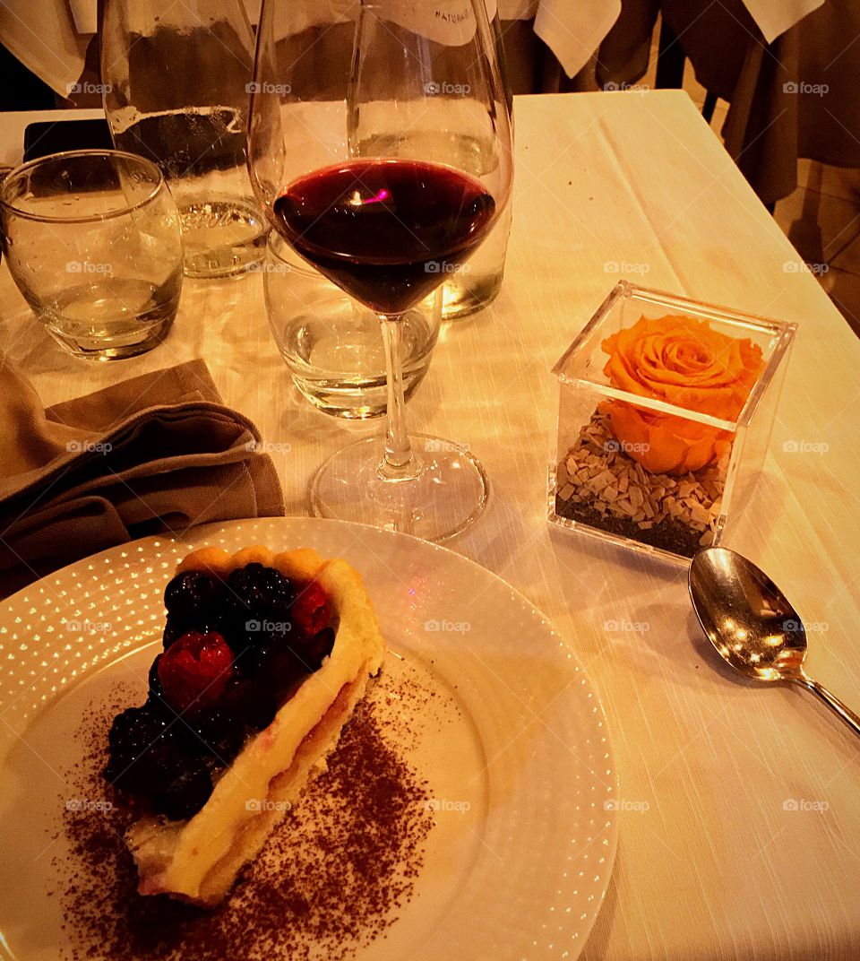Cake with berries, red wine and an orange rose.