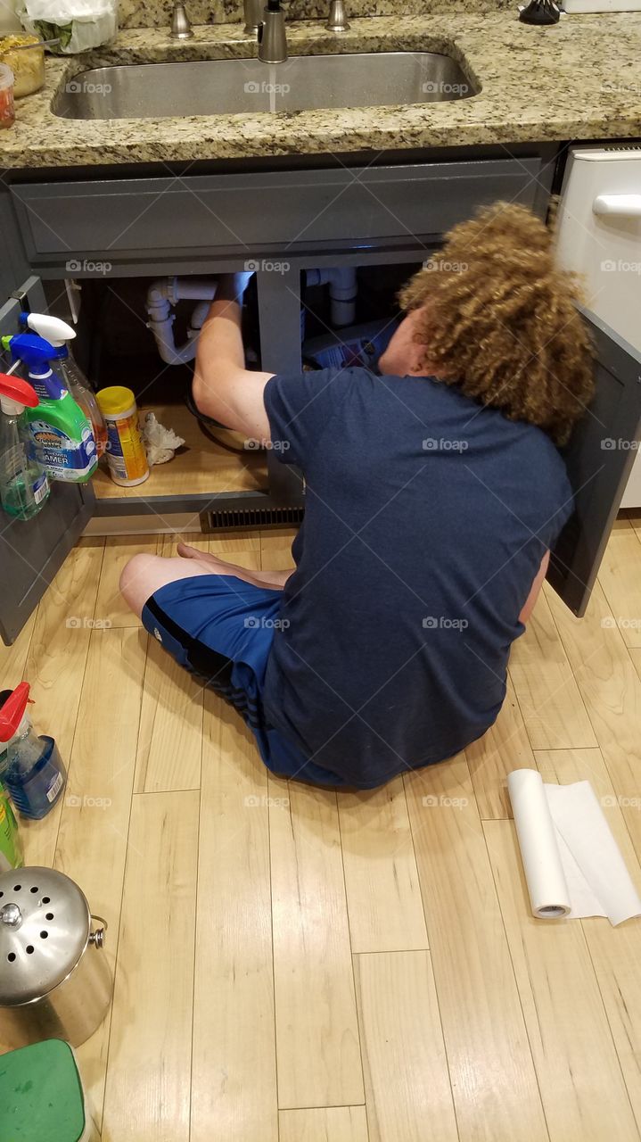 Man with curly hair fixing leaky sink