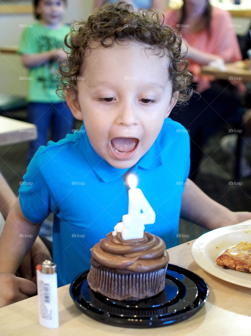 A little boy takes a big breath to blow out the candle on his fourth birthday. 