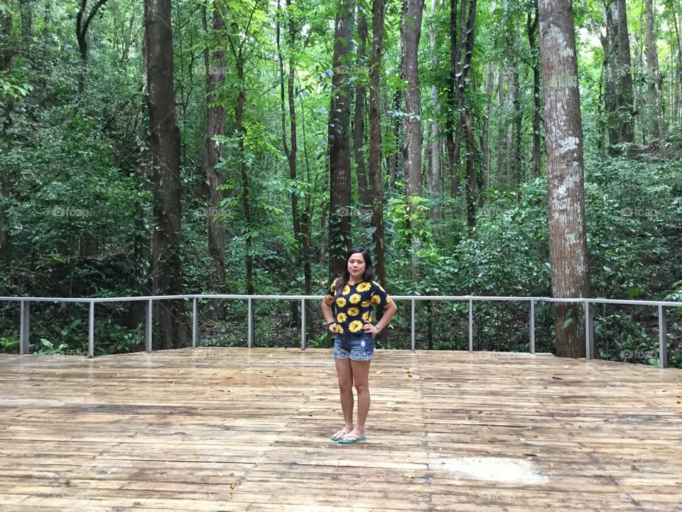 A girl tKing a simple post with the forest as it's background.