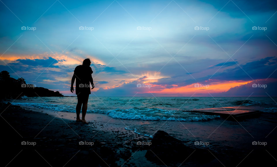 silhouette of a girl walking the beach at sunset.