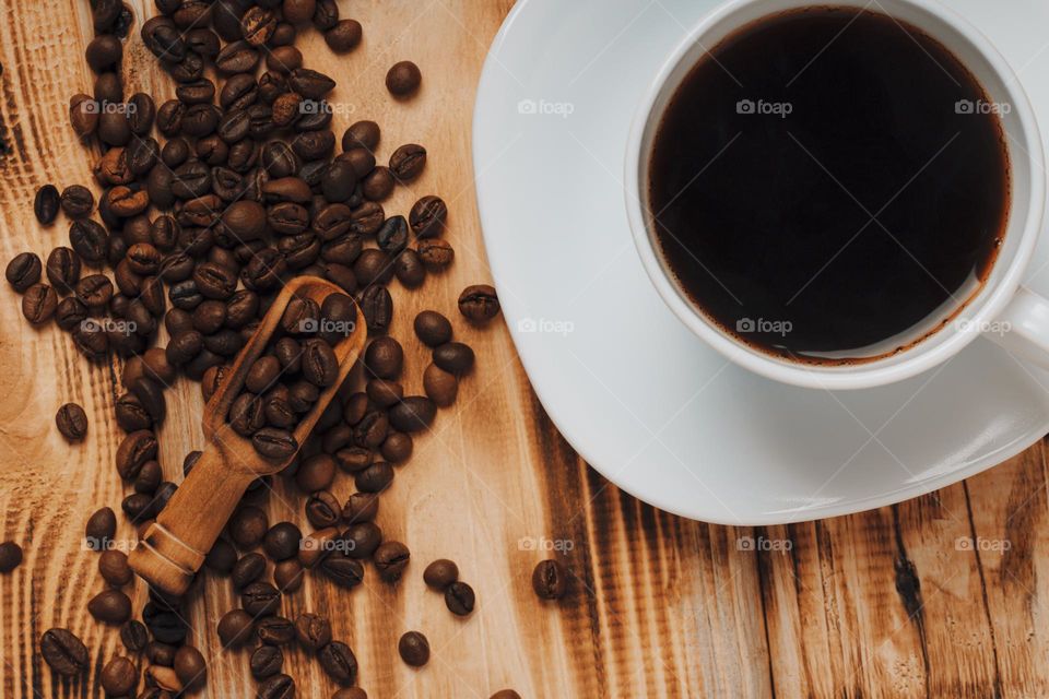 Top view of coffee cup and roasted coffee beans on wooden table