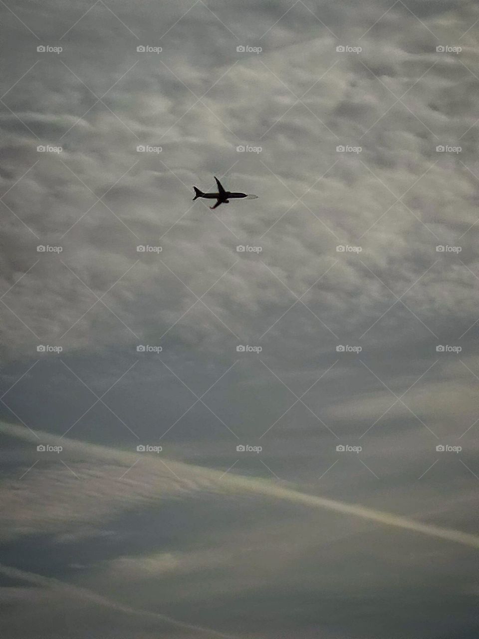 Black plane above gray clouds