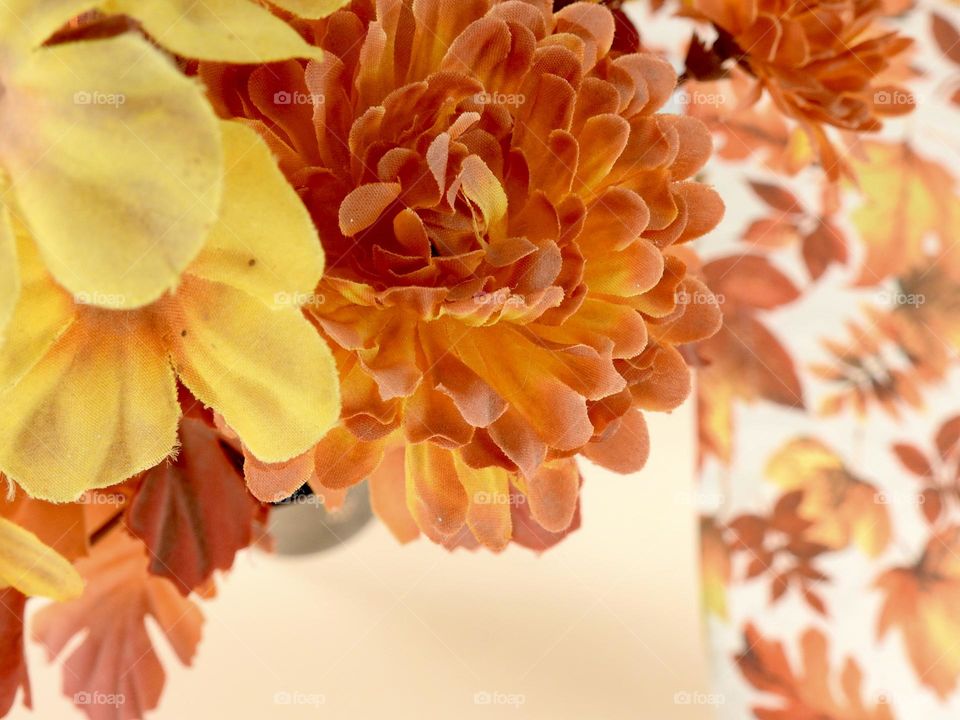 Orange yellow bouquet representing fall autumn on top of a beige background and cloth with orange leaves drawing with a blue and green tent during camping.