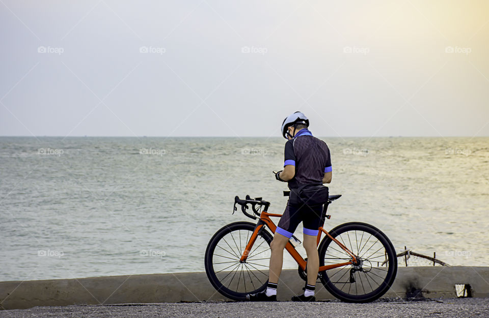 Man and a bicycle parked on the road by the sea In the morning.