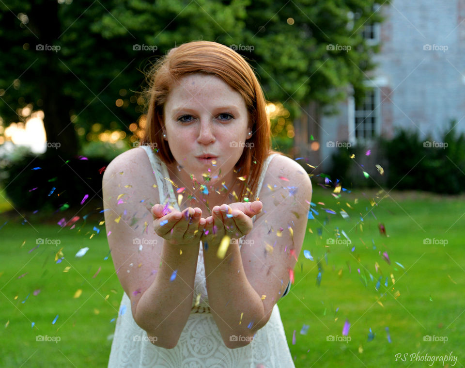 Woman blowing confetti in park