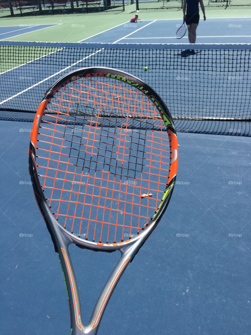 Tennis for fun. This is a Shot of the tennis racket while looking down at the court. 