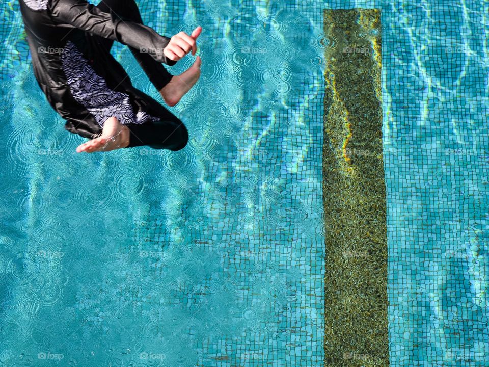 Close-up of a girl jumping into the pool on a sunny day