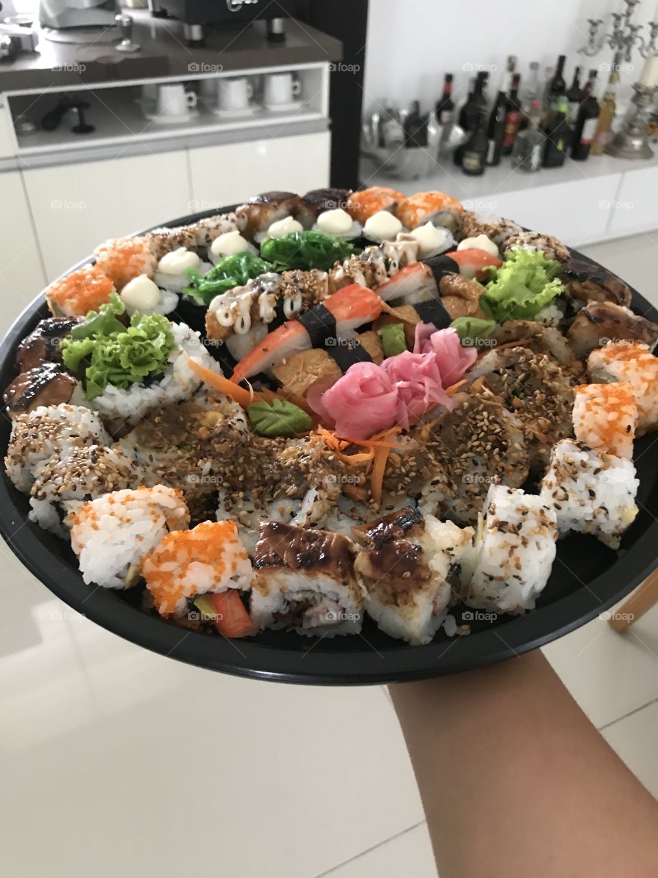 Hand is holding a plate of colorful sushi