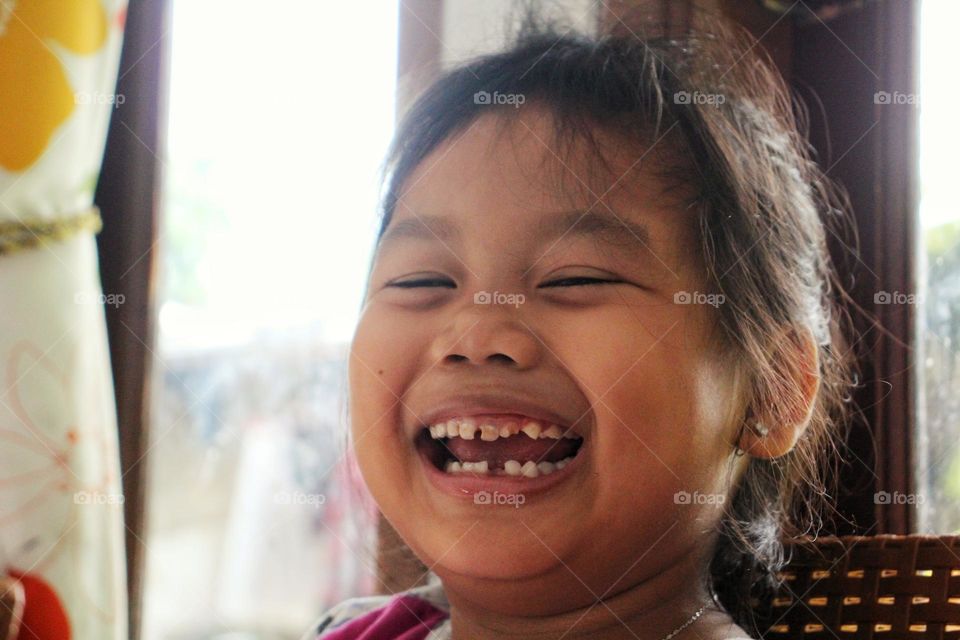 Little girl laughing with her missing teeth.