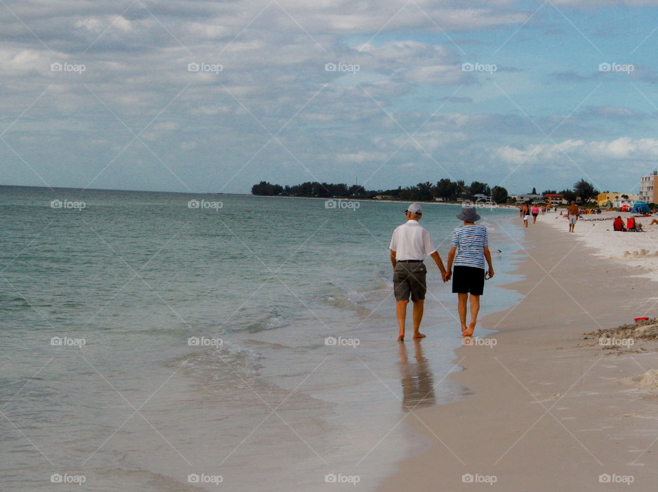 old couple walking on the beach