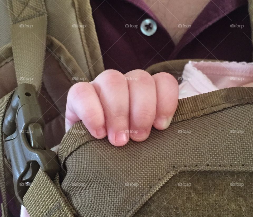 Baby fingers holding onto carrier
