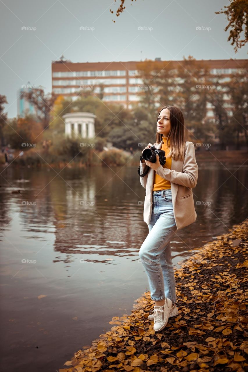 Young girl photographer in autumn park by the lake