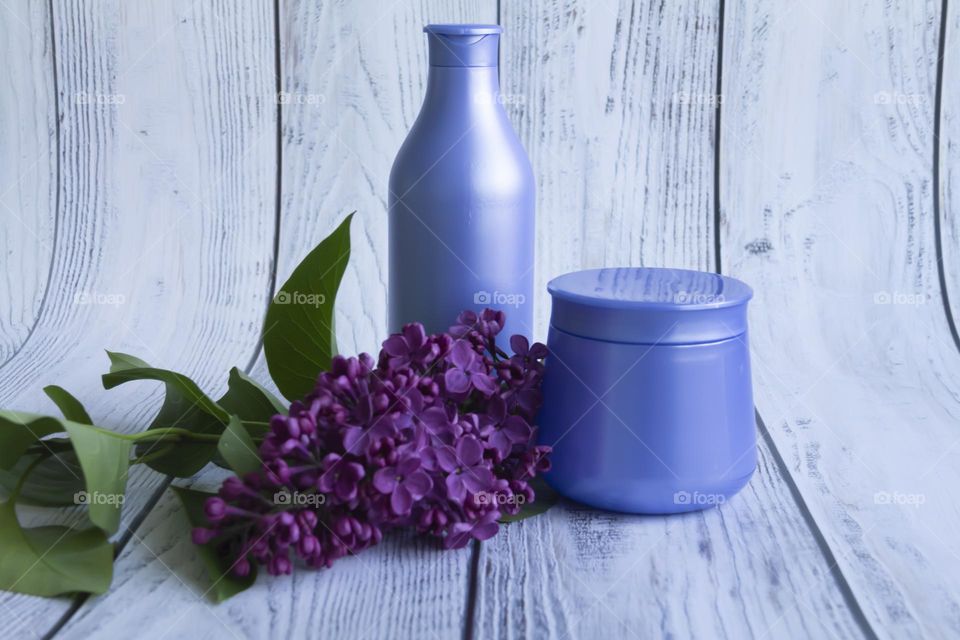 Spring, purple fragrant lilac with green leaves.  and jars with cosmetic cream and product.