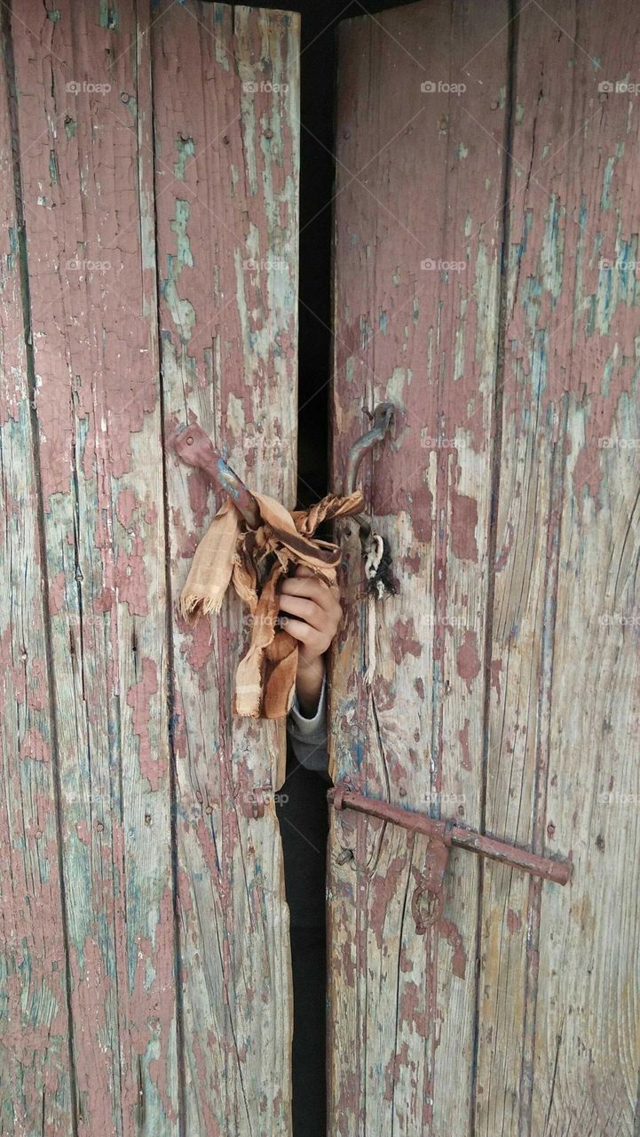 Human hand behind ancient door.