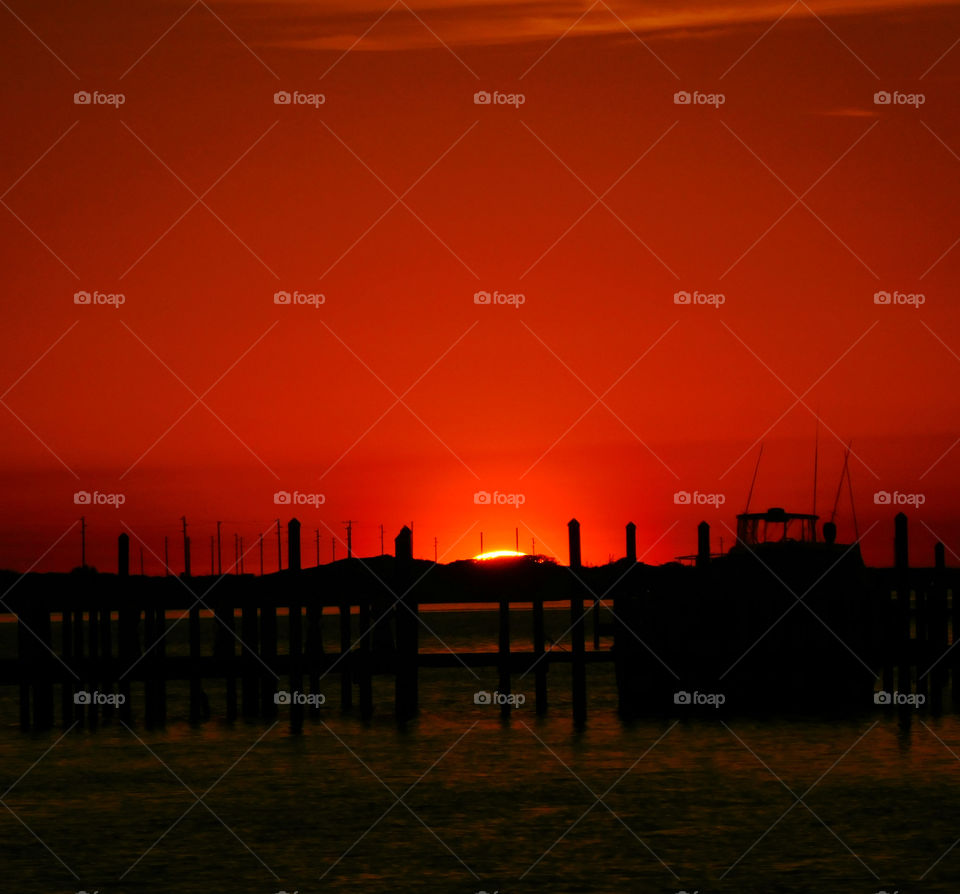 Silhouette of pier on sea at sunset