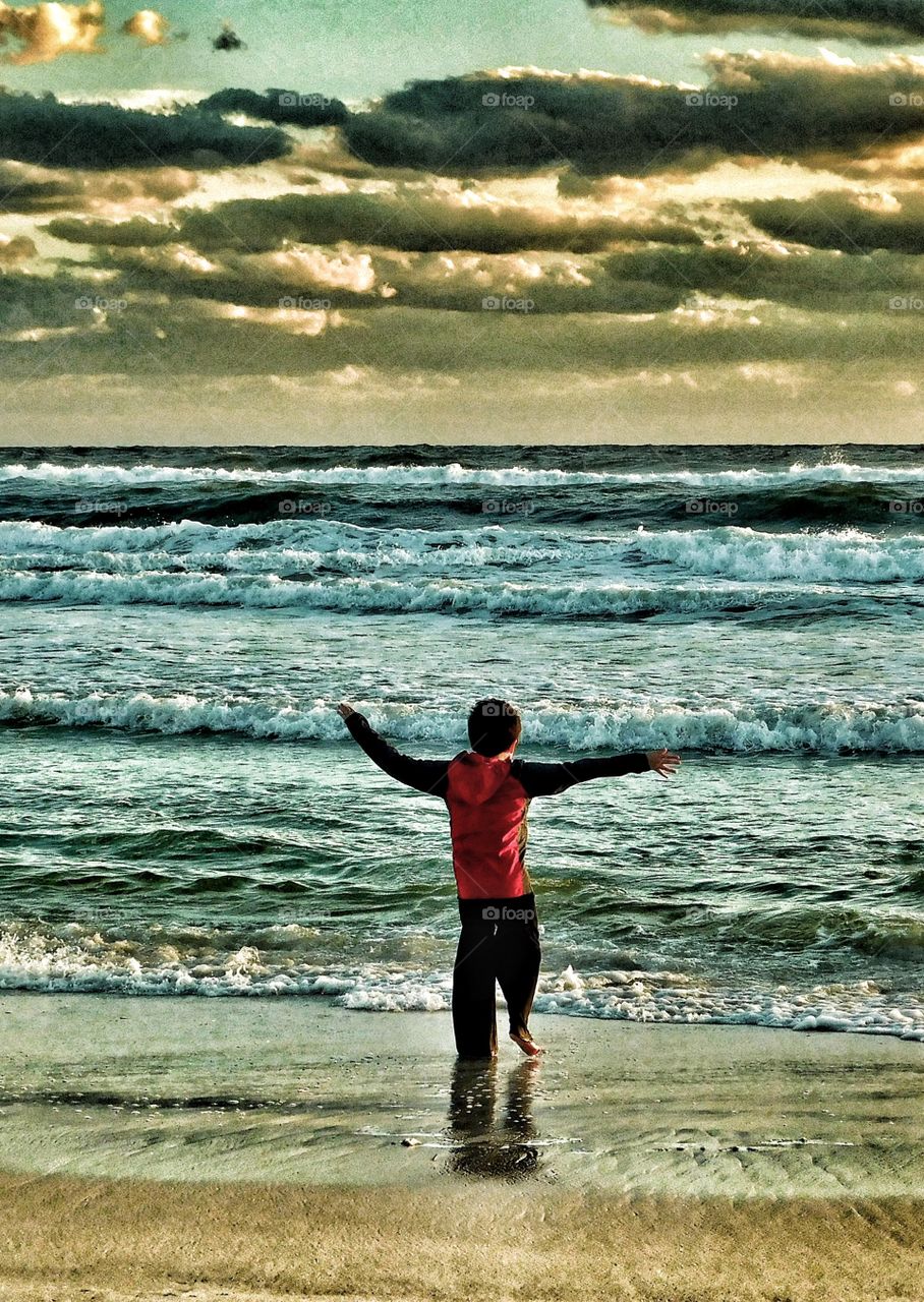 Rear view of a boy enjoying sunset at beach