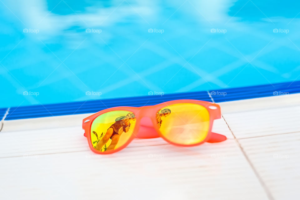 Summer sunglasses left on the edge of a swimming pool.