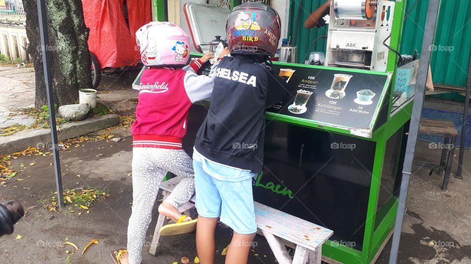 children buy tea milk brands of "Rasa Lain "on the side of the road