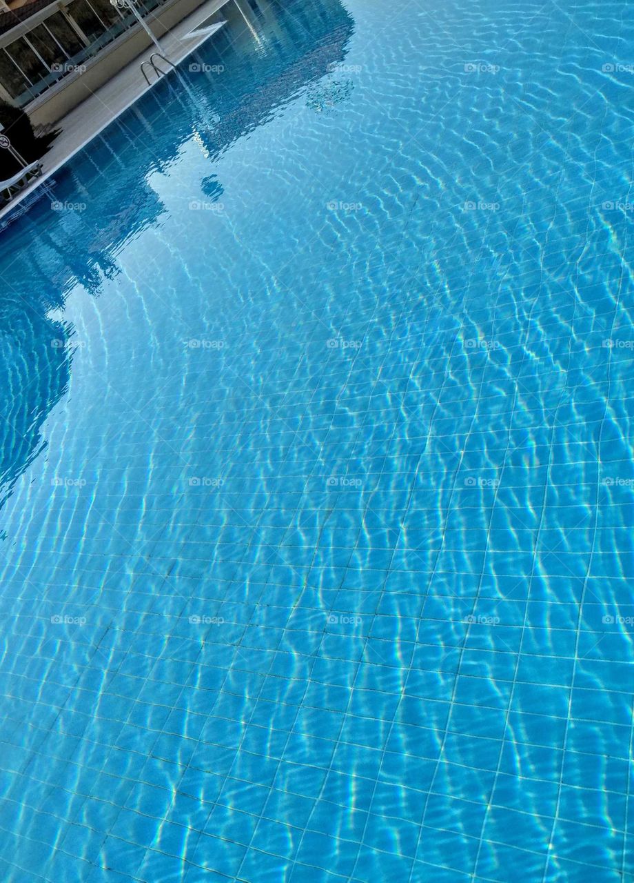 A swimming pool water in the fair day that was so beautiful blue with a few
waves, looks very clean and be attractive to us.