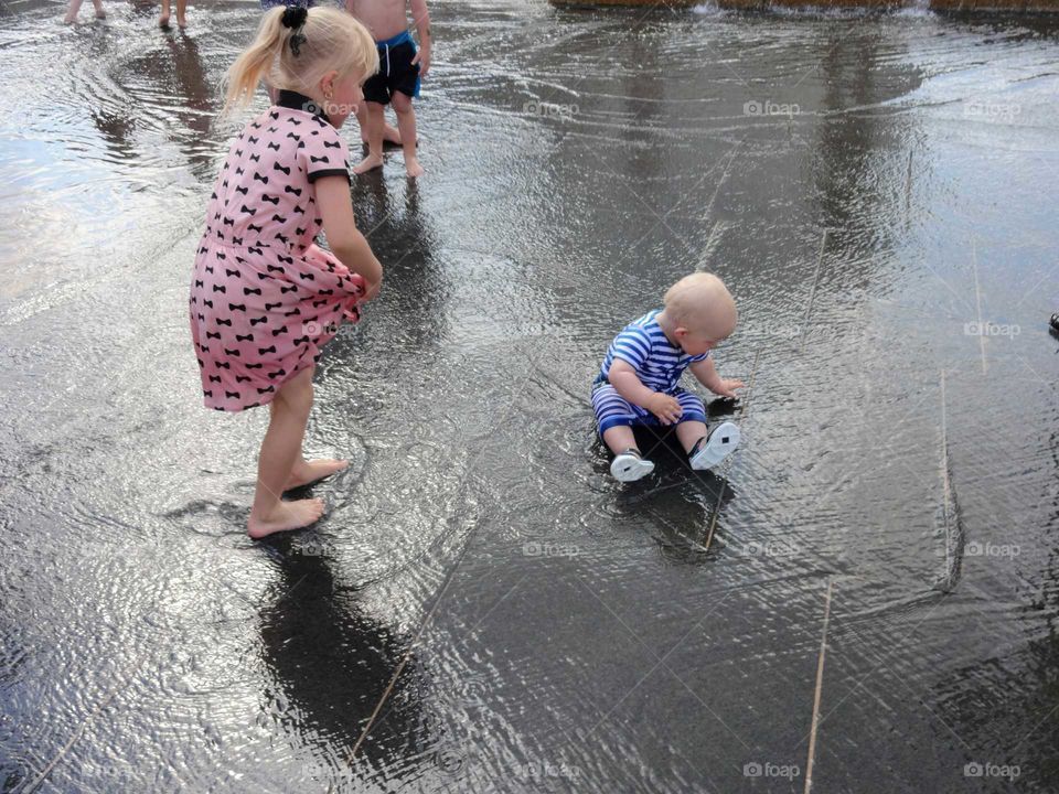 kids playing in water fountain in the Old Market Square, Nottingham city centre UK