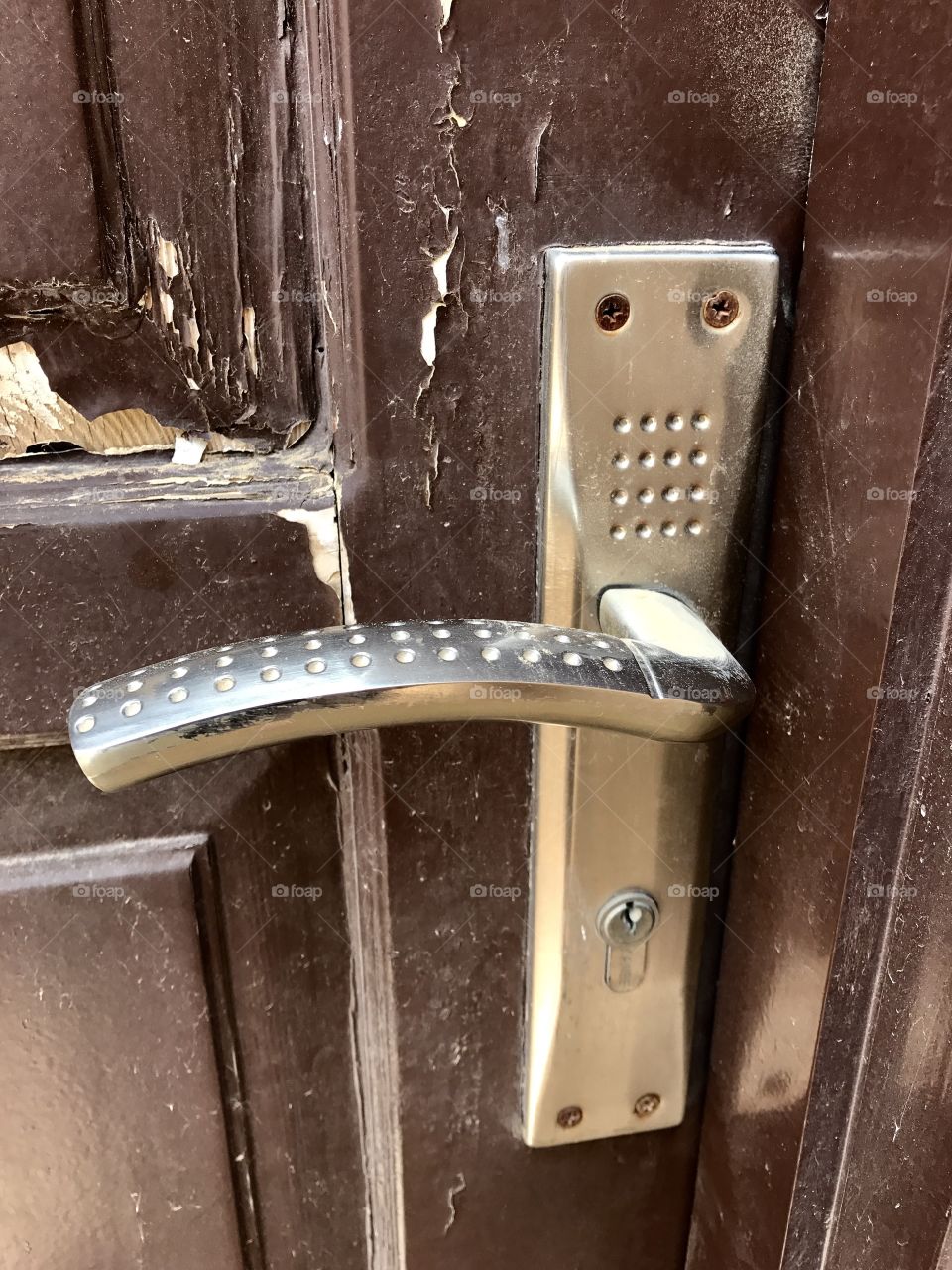 Silver Door handle Middle East on brown paint flaked door 