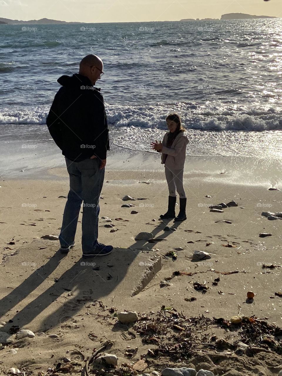 A father talking to daughter on the seaside.