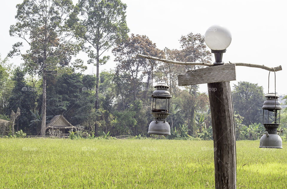 Old lantern hanging on wooden background fields.