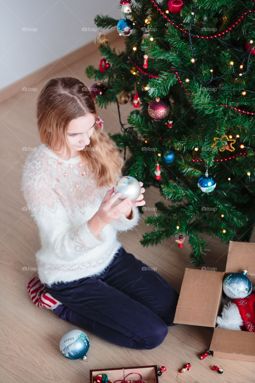 Young woman sitting near christmas tree